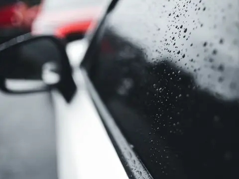 Raindrops on the side glass beside a car mirror