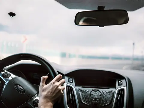 Hand on the wheel driving with a bright windshield